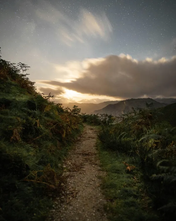 mountain path with sun emerging from clouds