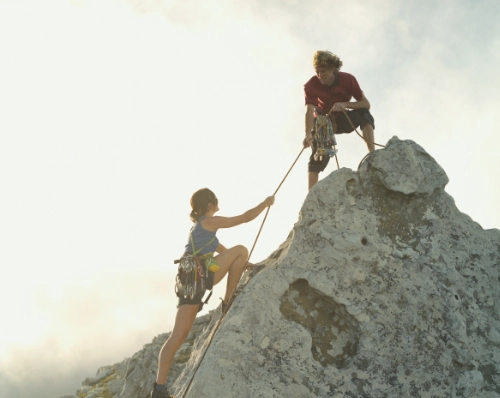 one climber helping another climber with a rope