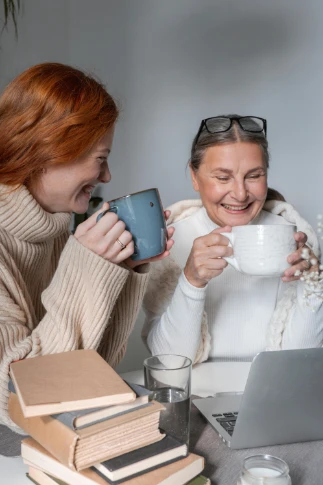 young woman smiling drinking coffee with older smiling woman